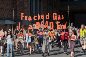 Student protesters marching. A sign says "Fracked Gas Is a DEAD End. 