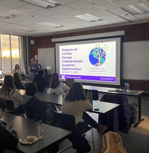 A photo of people watching a slides presentation from the Program on Climate Change.
