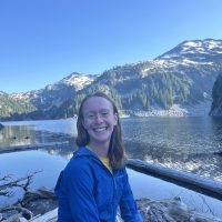 Photo of Amelia sitting in a boat on a lake with mountains in the background