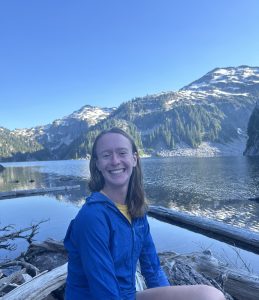 Photo of Amelia sitting in a boat on a lake with mountains in the background