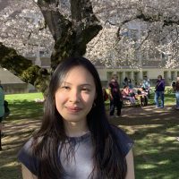 Photo of Cassia smiling with blooming cherry blossoms in the background