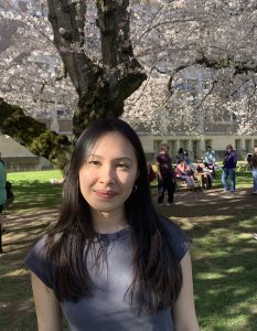 Photo of Cassia smiling with blooming cherry blossoms in the background