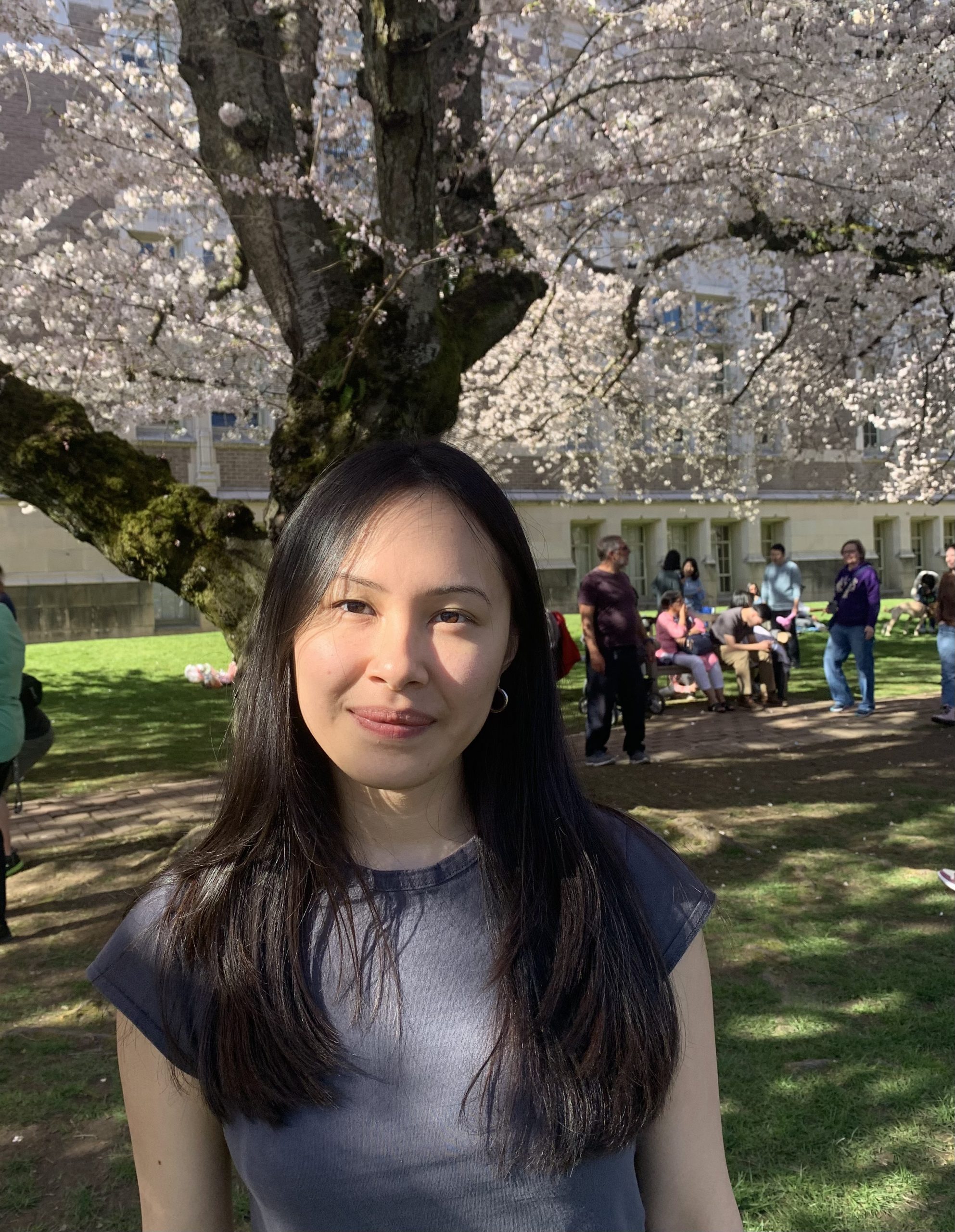 Photo of Cassia smiling with blooming cherry blossoms in the background