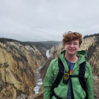 Photo of Dana smiling on a hike with a gorge in the background