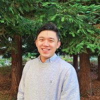 Photo of Chin-Wei Chen smiling with tress in the background