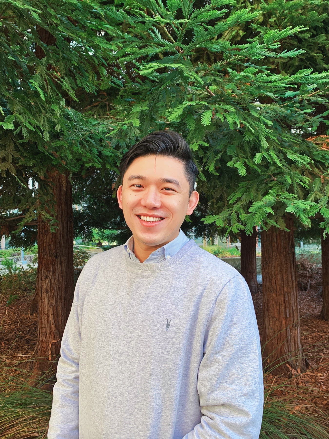 Photo of Chin-Wei Chen smiling with tress in the background