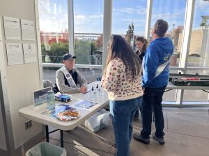 A photo from the reception of attendees talking to a host at an activities table.