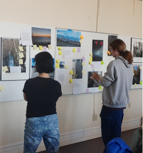 Two people looking at photos of water, including a creek, seashore, storm run-off, and urban river.